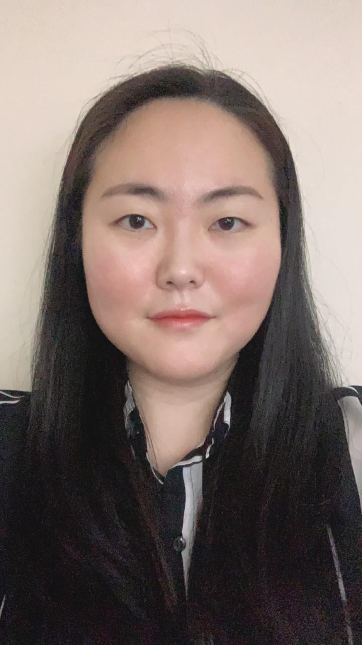 Doctoral Intern Kitty Wang smiling at the camera wearing a black and white striped blouse in front of a beige background