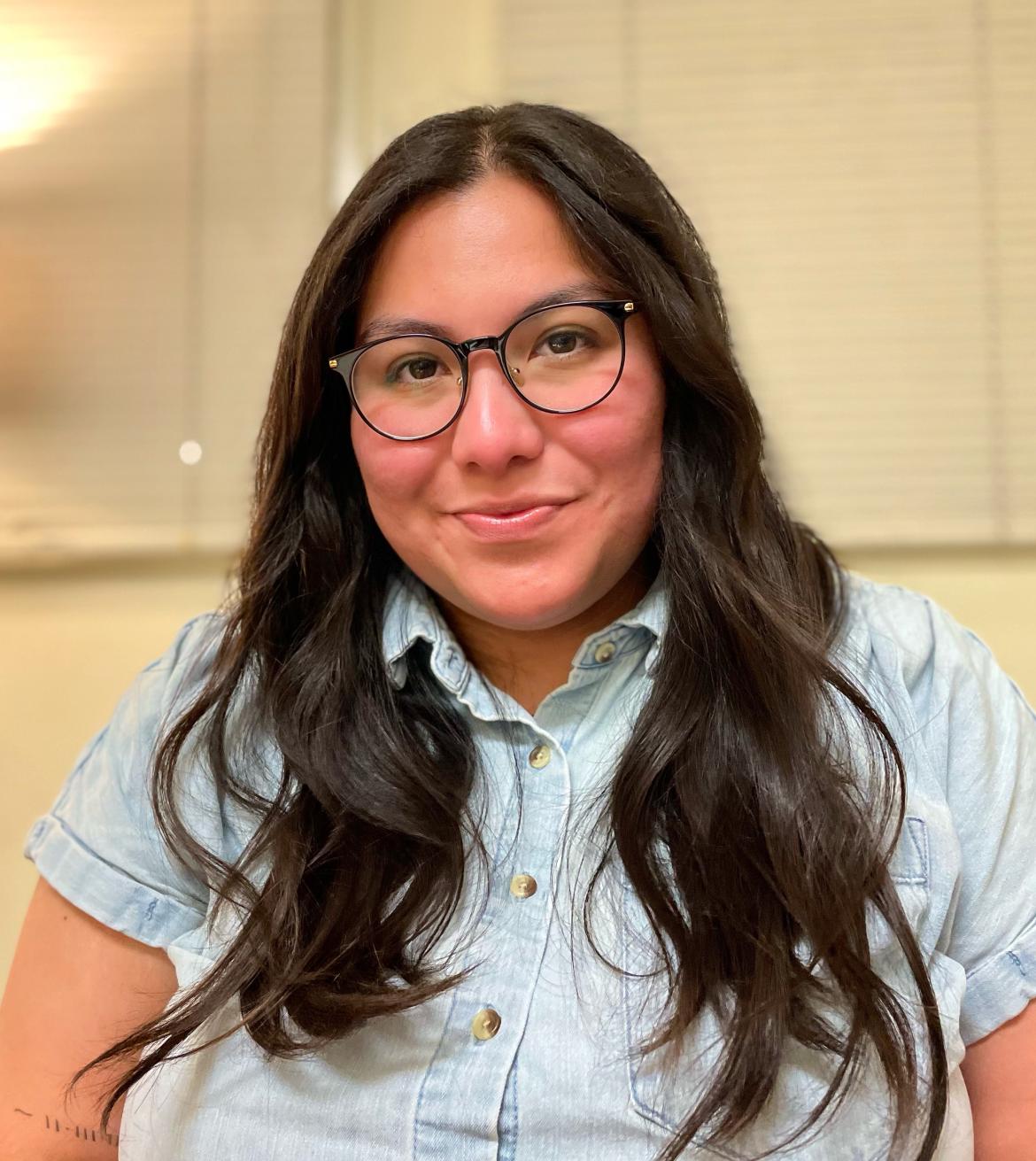 Social work intern Elisa Espinoza smiling at the camera wearing a blue button up shirt 