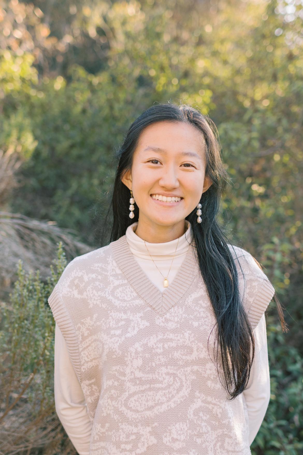 Practicum student Michelle Chang wearing a beige sweater vest over a beige long sleeve smiling at the camera