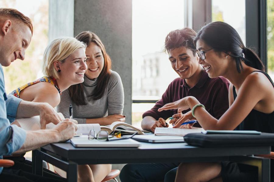 A group of five students sitting around a table having a conversation